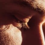 Closeup of a man looking down, simulating the discomfort of dry eye syndrome.