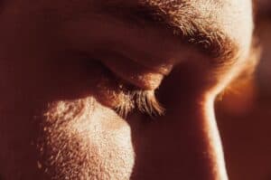 Closeup of a man looking down, simulating the discomfort of dry eye syndrome.