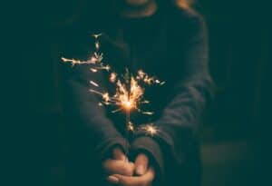 A person using a sparkler during a Fourth of July celebration, wearing protective eyewear.