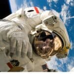 An astronaut floating in space with Earth in the background, symbolizing space travel eye health.