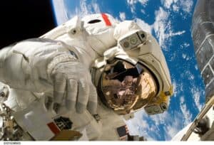 An astronaut floating in space with Earth in the background, symbolizing space travel eye health.