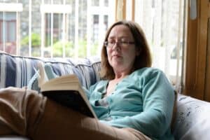 Woman wearing reading glasses while reading a book, representing an ideal candidate for presbyopia eye drop treatment